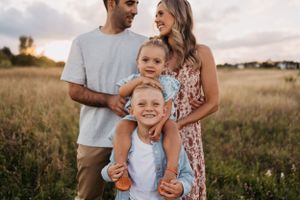 Candid family moment captured in a summer meadow during golden hour.