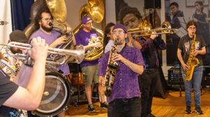 Brass band performs energetically with trumpets and other instruments on stage.