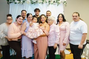 Family photo session with coordinated pink and white outfits under floral arch decor.