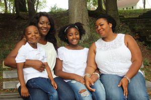 Family group sits casually together on outdoor steps wearing coordinated white and denim outfits.