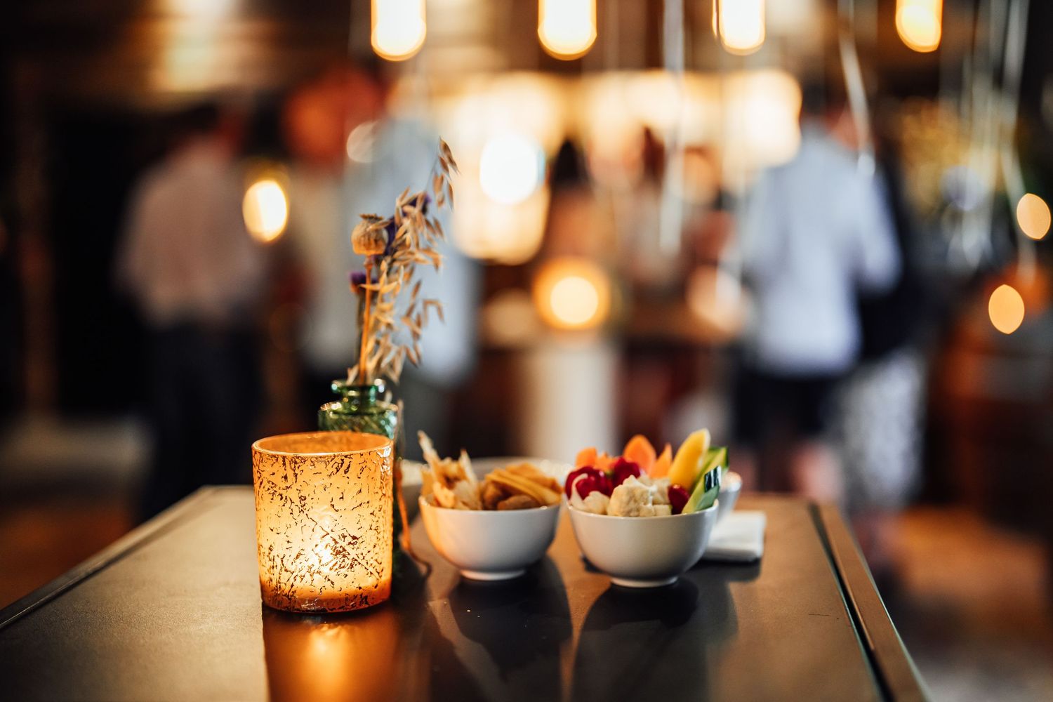 Cozy restaurant table setting with glowing candle and small dishes in warm ambient lighting.