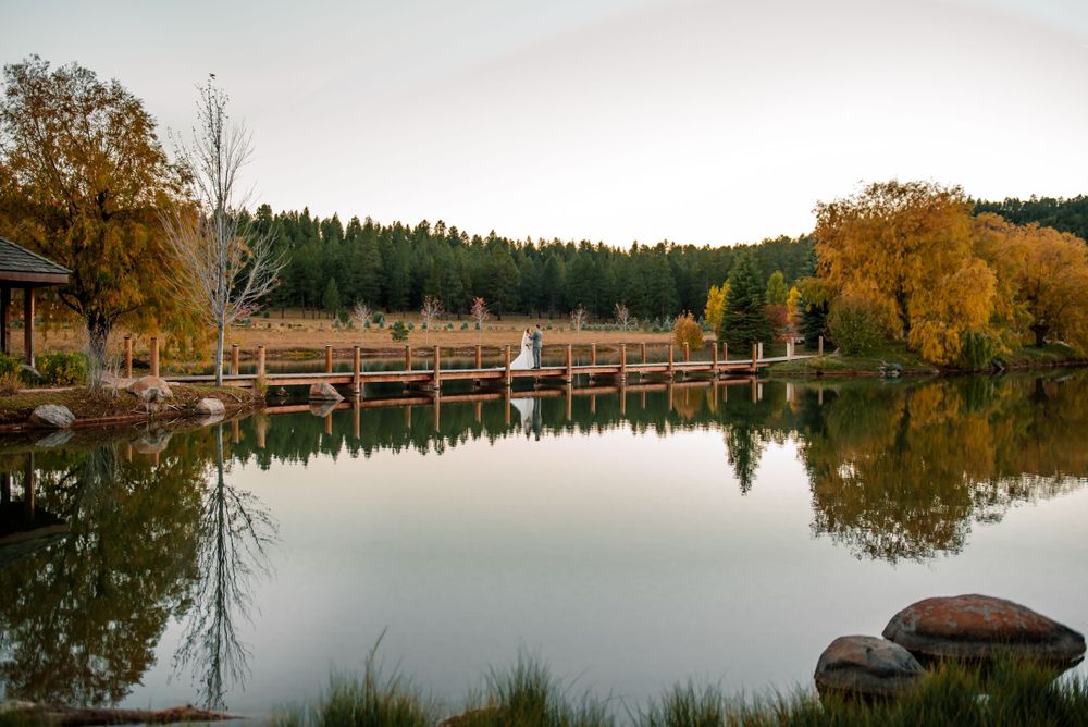 Panoramic autumn landscape with golden trees reflecting in a calm lake at sunset.