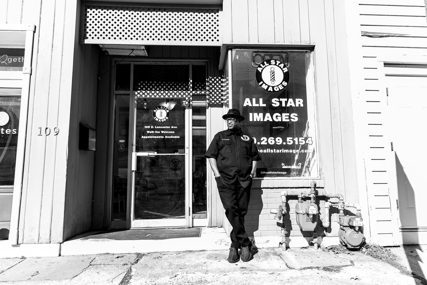 Black and white photo of a person standing outside a storefront.