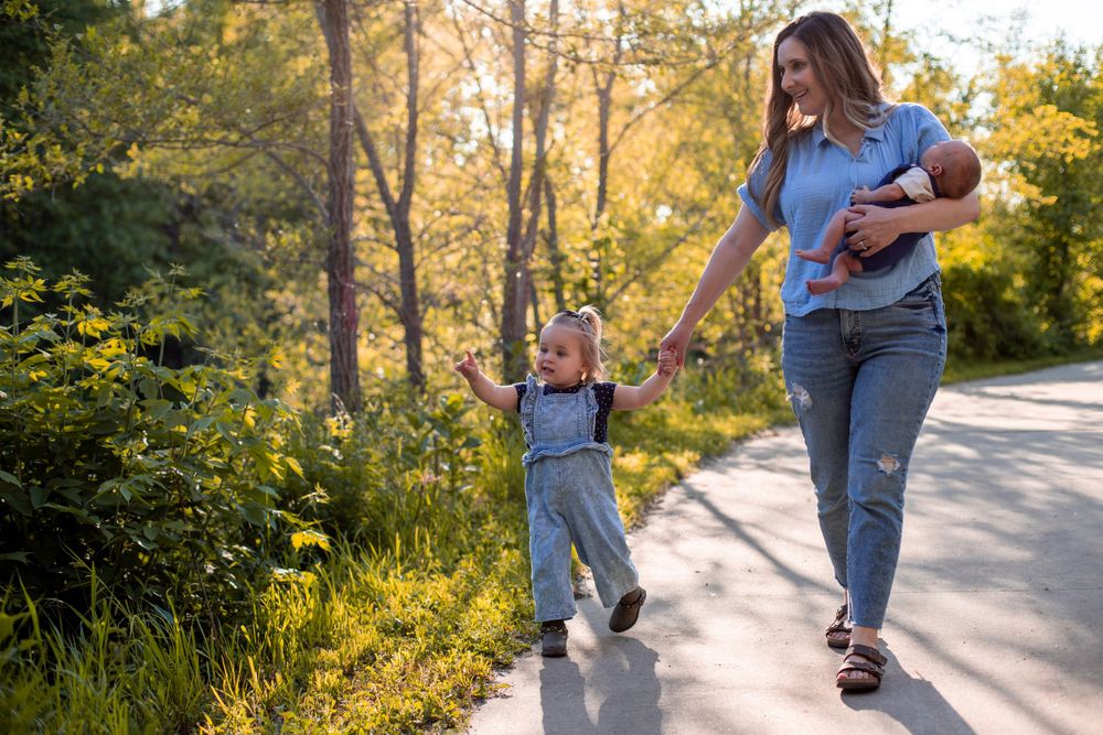 Mother and toddler walking hand in hand on sunny path with beautiful golden light.