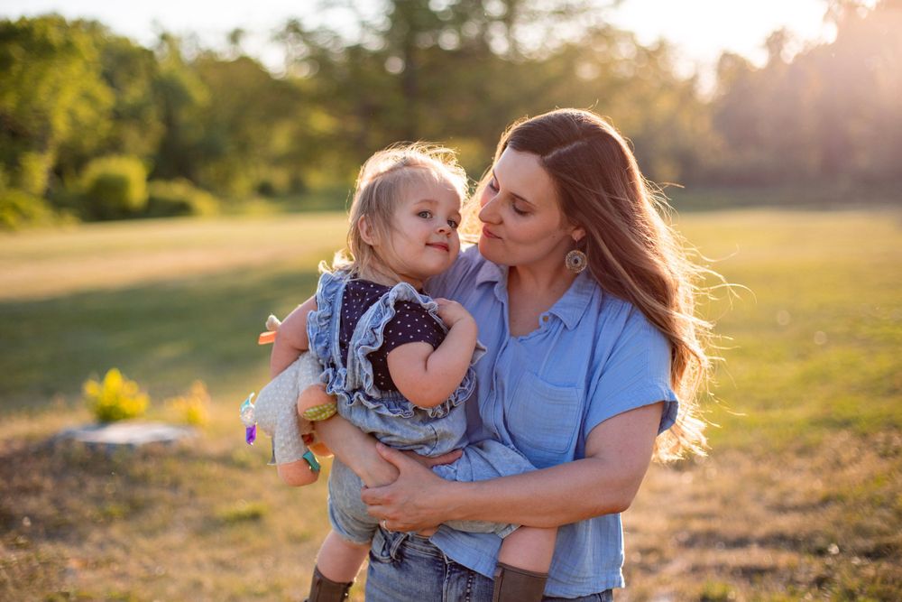 A tender moment between parent and child captured in golden sunset light outdoors.