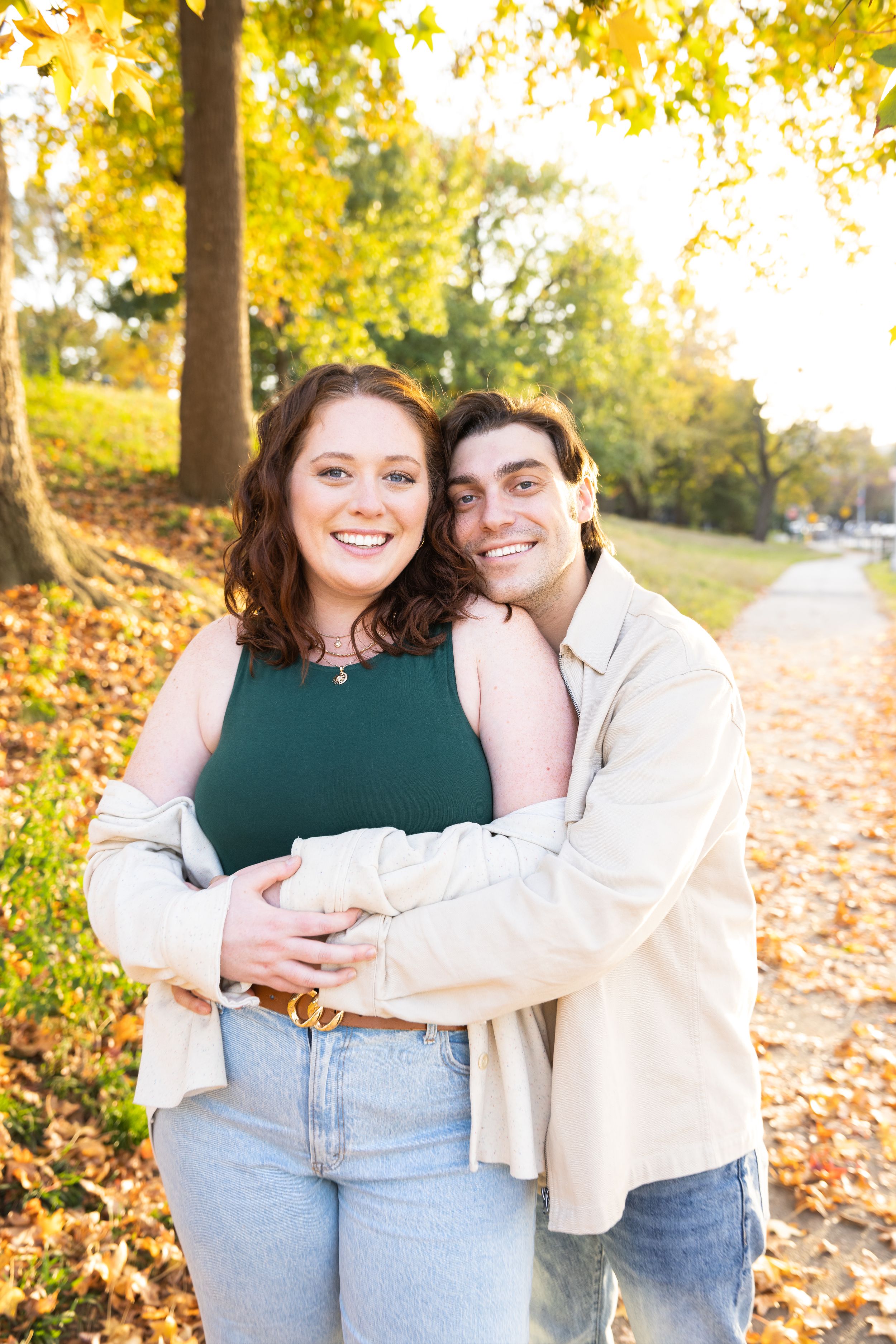 Happy couple hugging and smiling in colorful autumn park with golden foliage background.