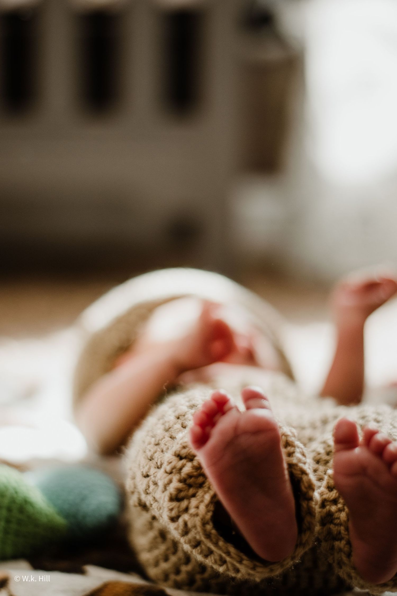 Tiny baby feet wrapped in knitted blanket with soft focus background.