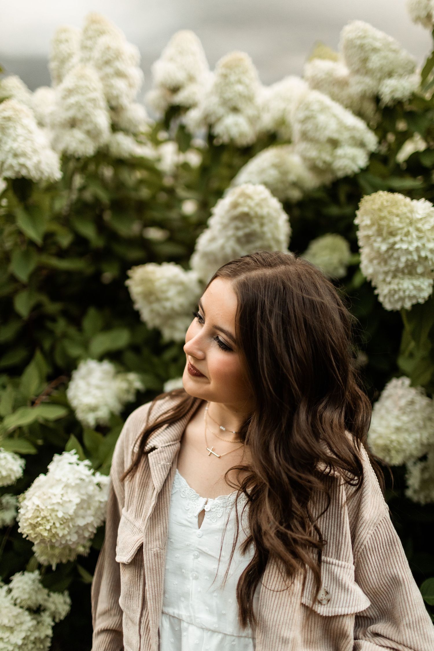 A portrait against blooming white hydrangea bushes showing delicate springtime beauty.