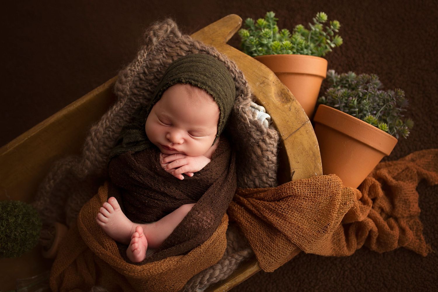 baby boy photoshoot wrapped in brown blanket in trench bowl