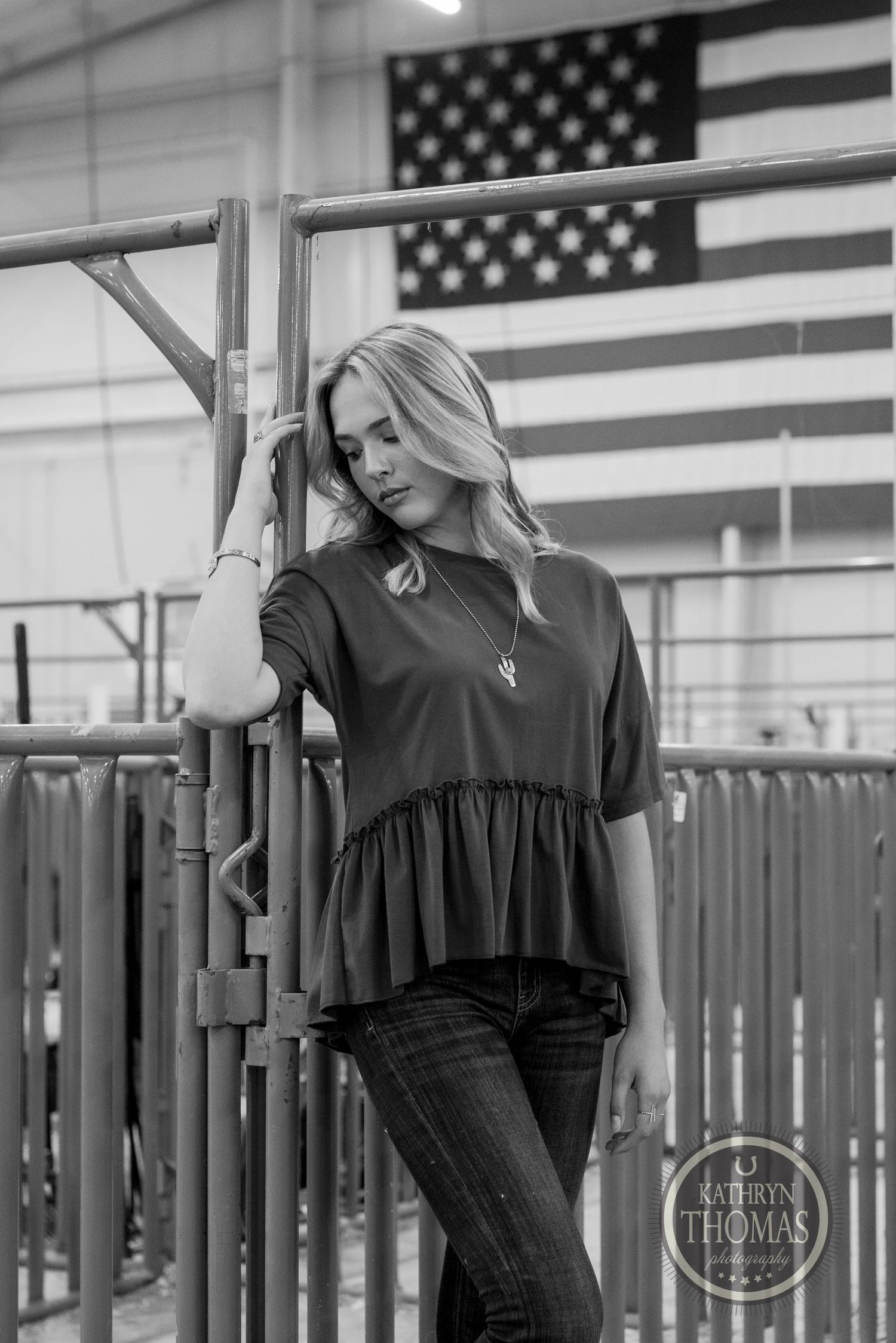 Black and white fashion portrait against flag features teal top and relaxed pose.