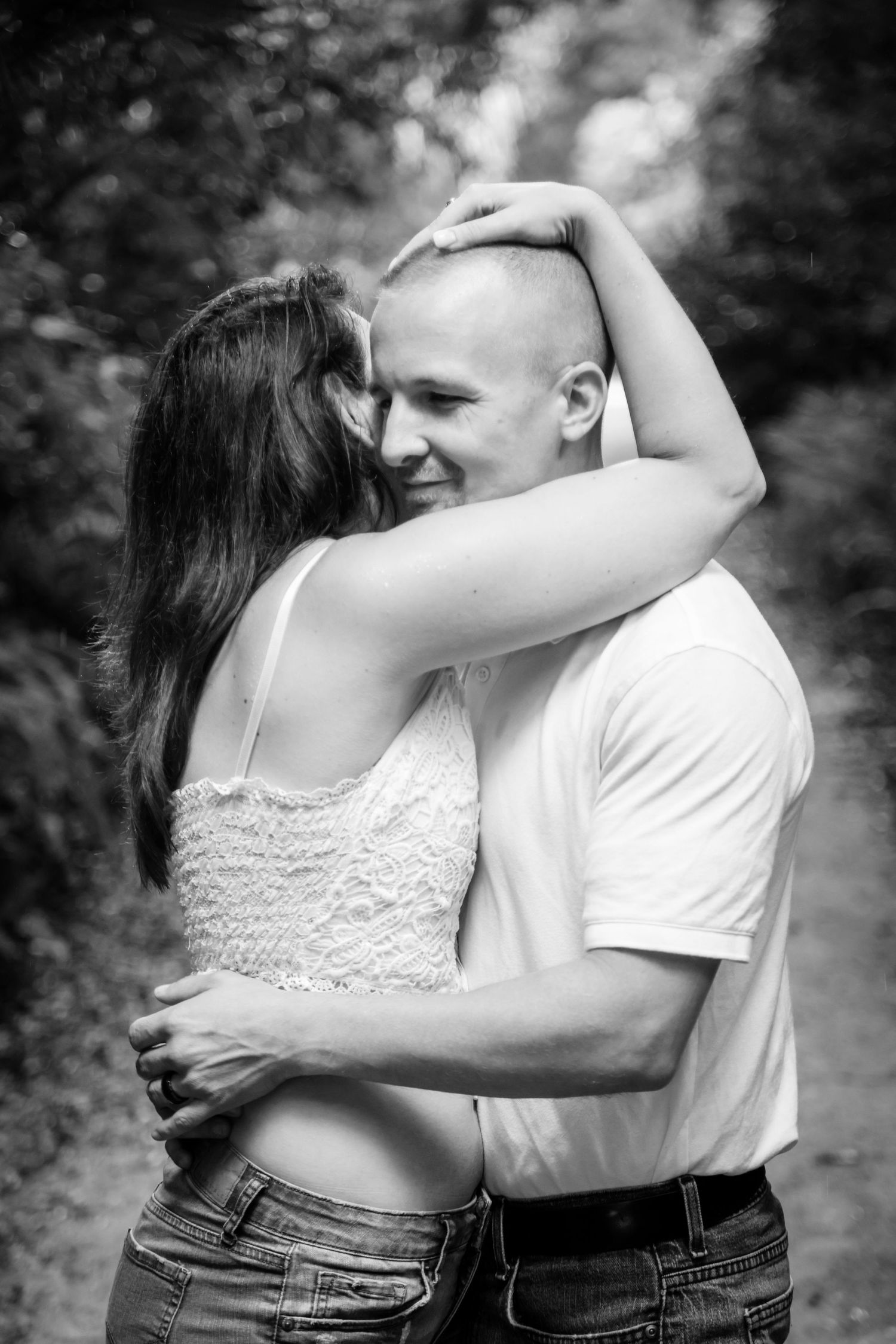 An intimate black and white portrait of a couple embracing outdoors.