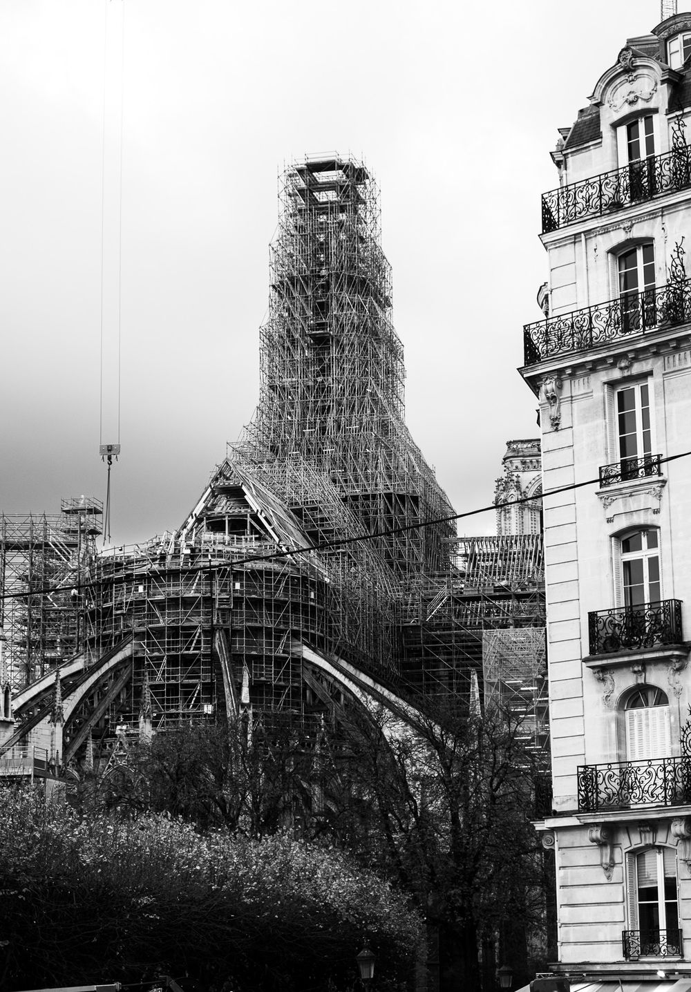 Black and white image of Notre-Dame Cathedral spire reconstruction surrounded by scaffolding in Paris.