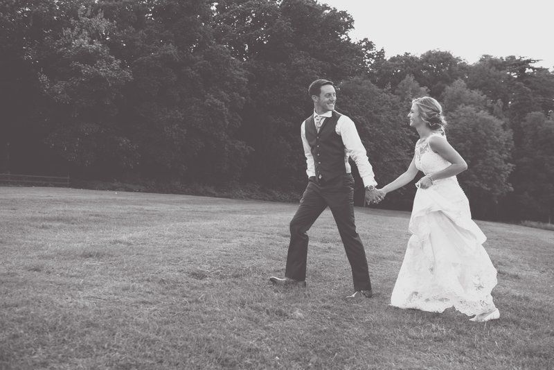 Couple dances playfully on a grassy field during their wedding photoshoot.