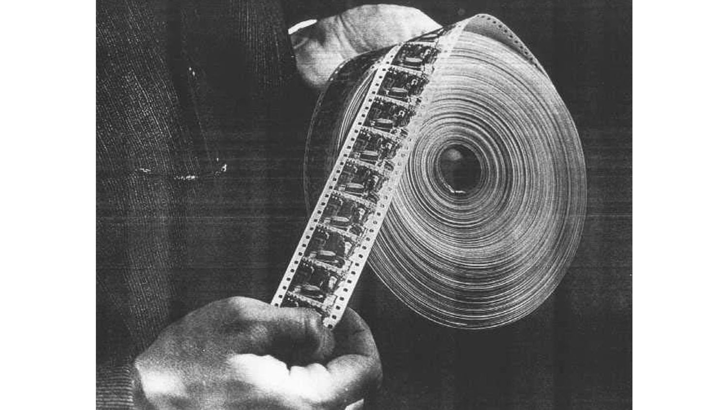 Film strip being unrolled to show spiral pattern in black and white photograph.