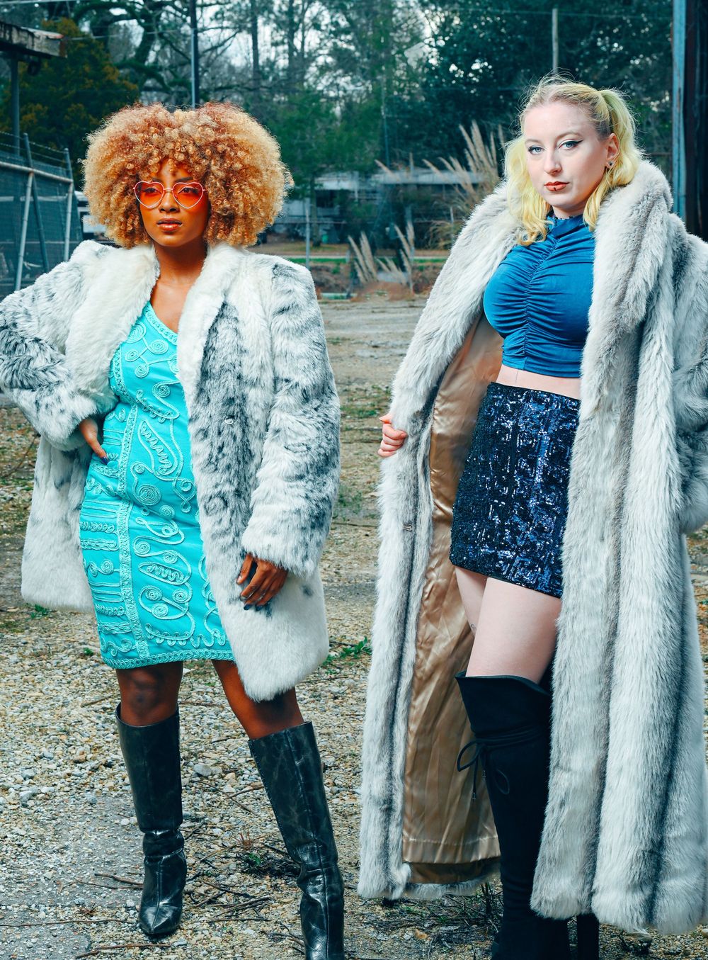 Two models in winter fashion pose outdoors wearing plush fur coats and trendy outfits against forest backdrop.