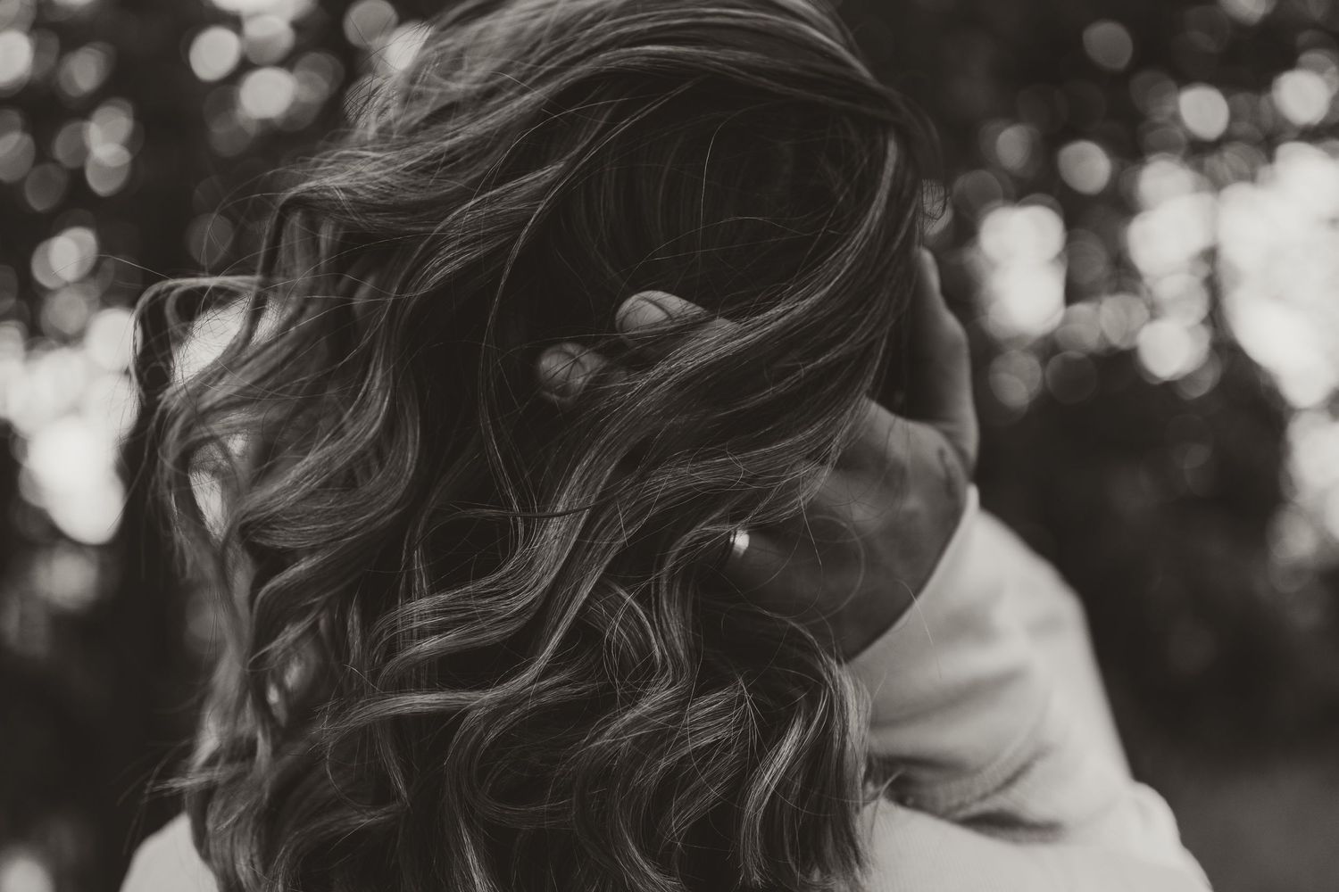 Close-up shot of long wavy brown hair with soft bokeh lights in the background.