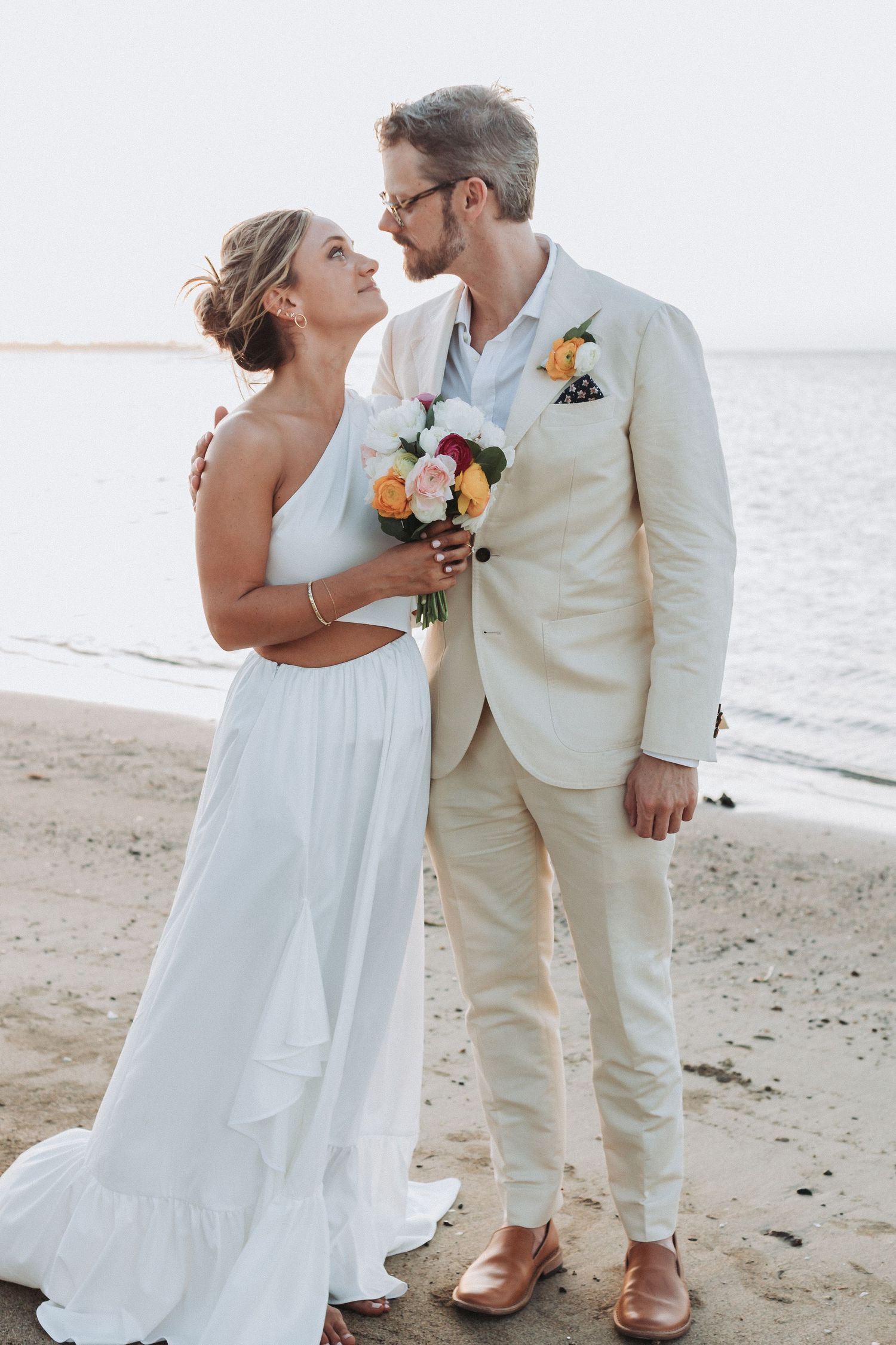 A tender moment between newlyweds on a serene beach at sunset.