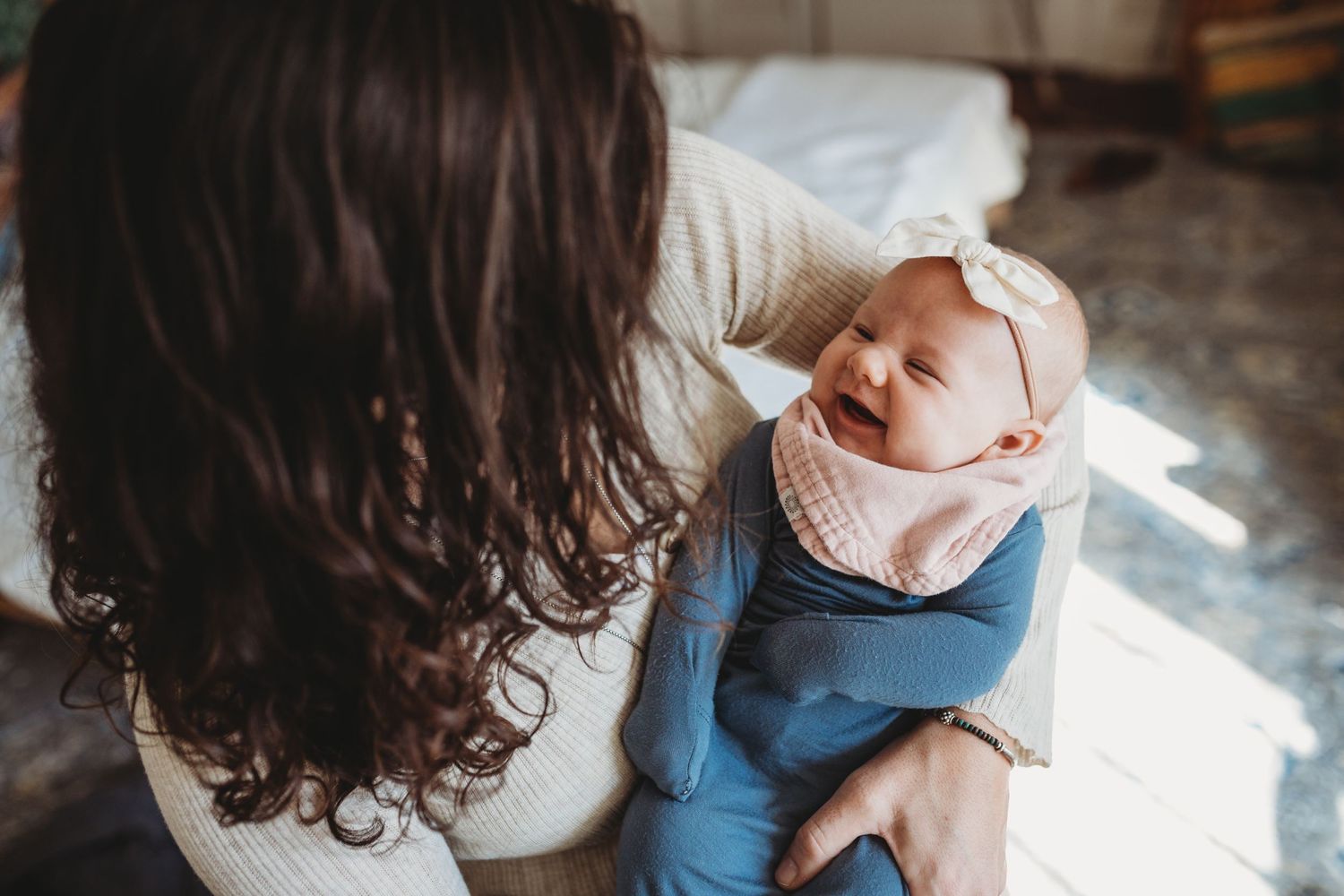 Mother holds a baby girl who is smiling and laughing