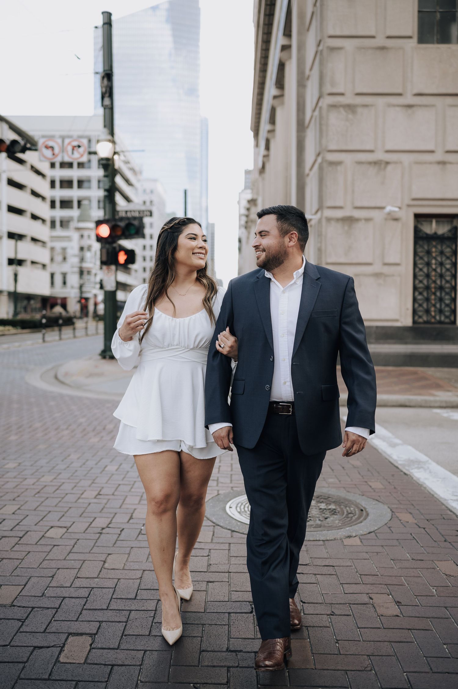 Houston area couple's engagement session. They are holding hands and walking across Franklin Street in downtown.