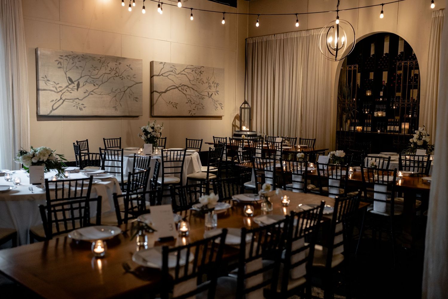 Elegant wedding reception venue with dark wood chairs and string lighting.