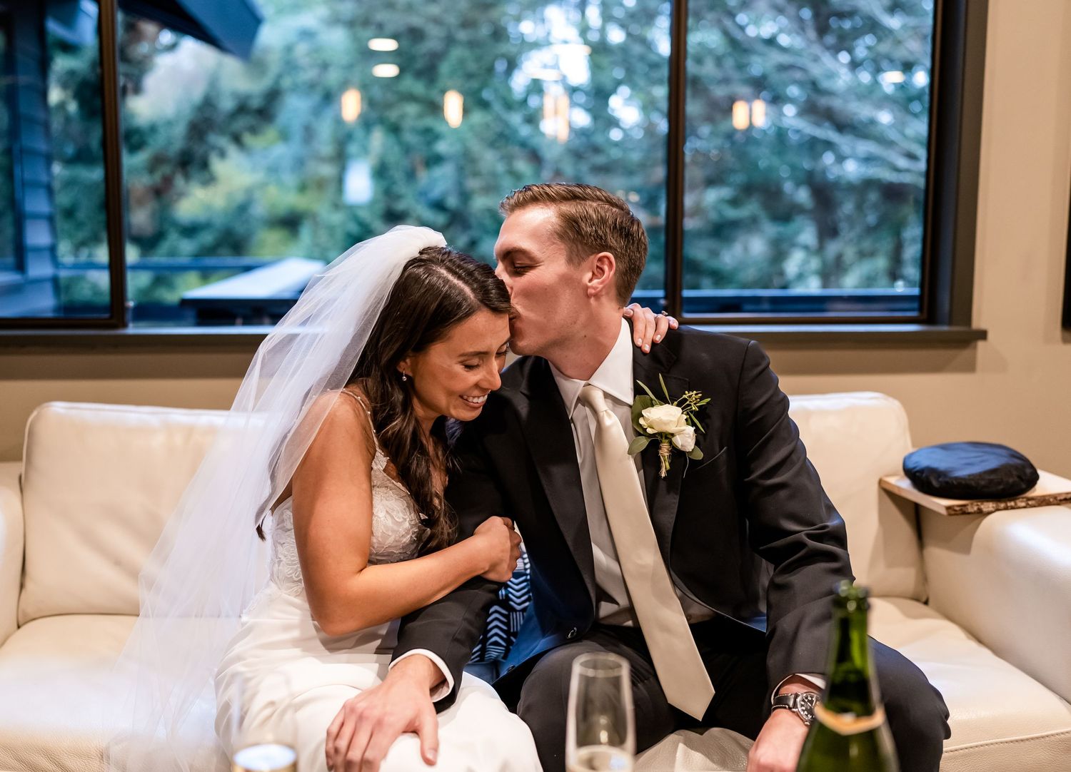 Intimate moment on a white couch at a wedding reception with champagne glasses.
