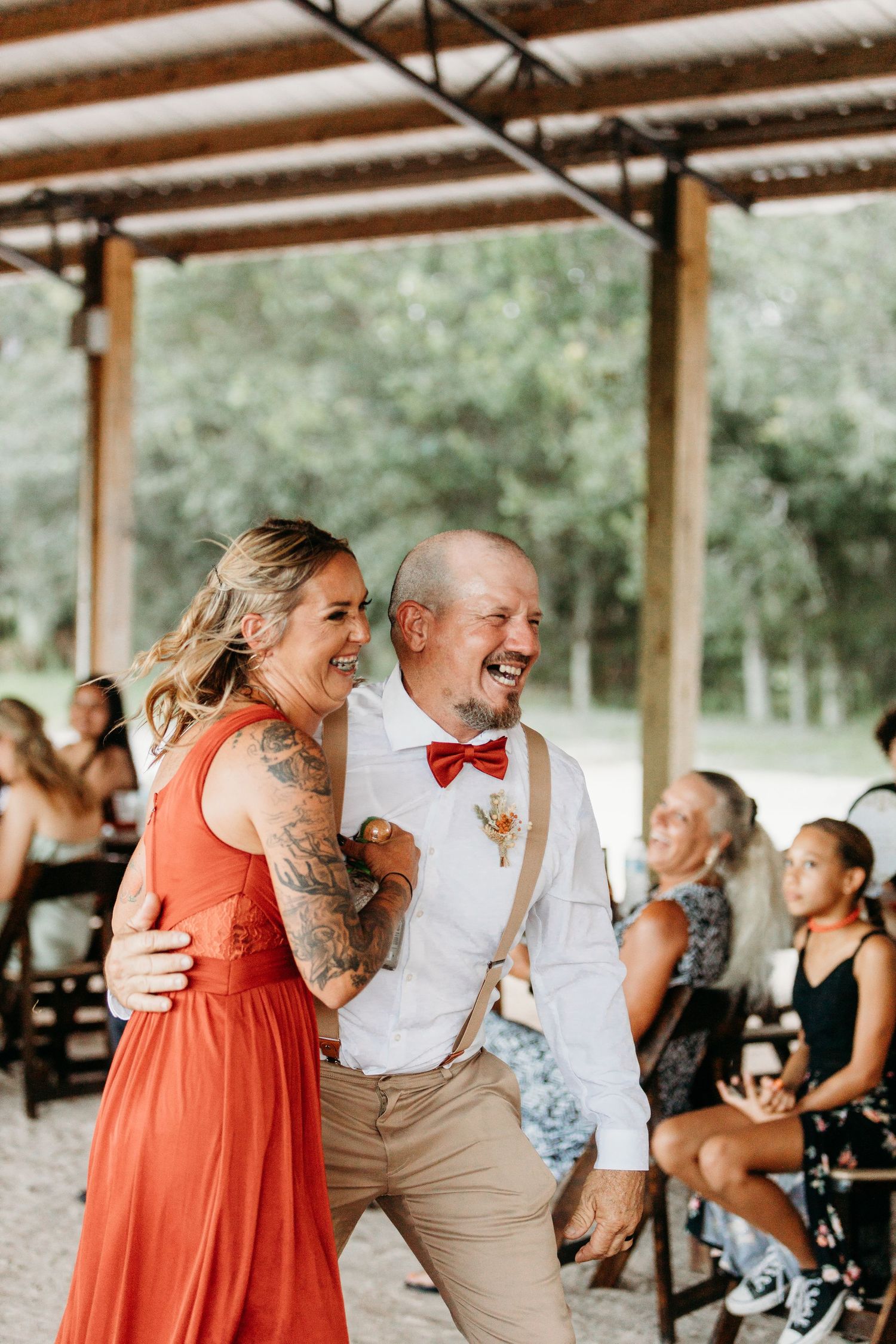 A couple shares a joyful moment dancing together at a rustic barn reception.