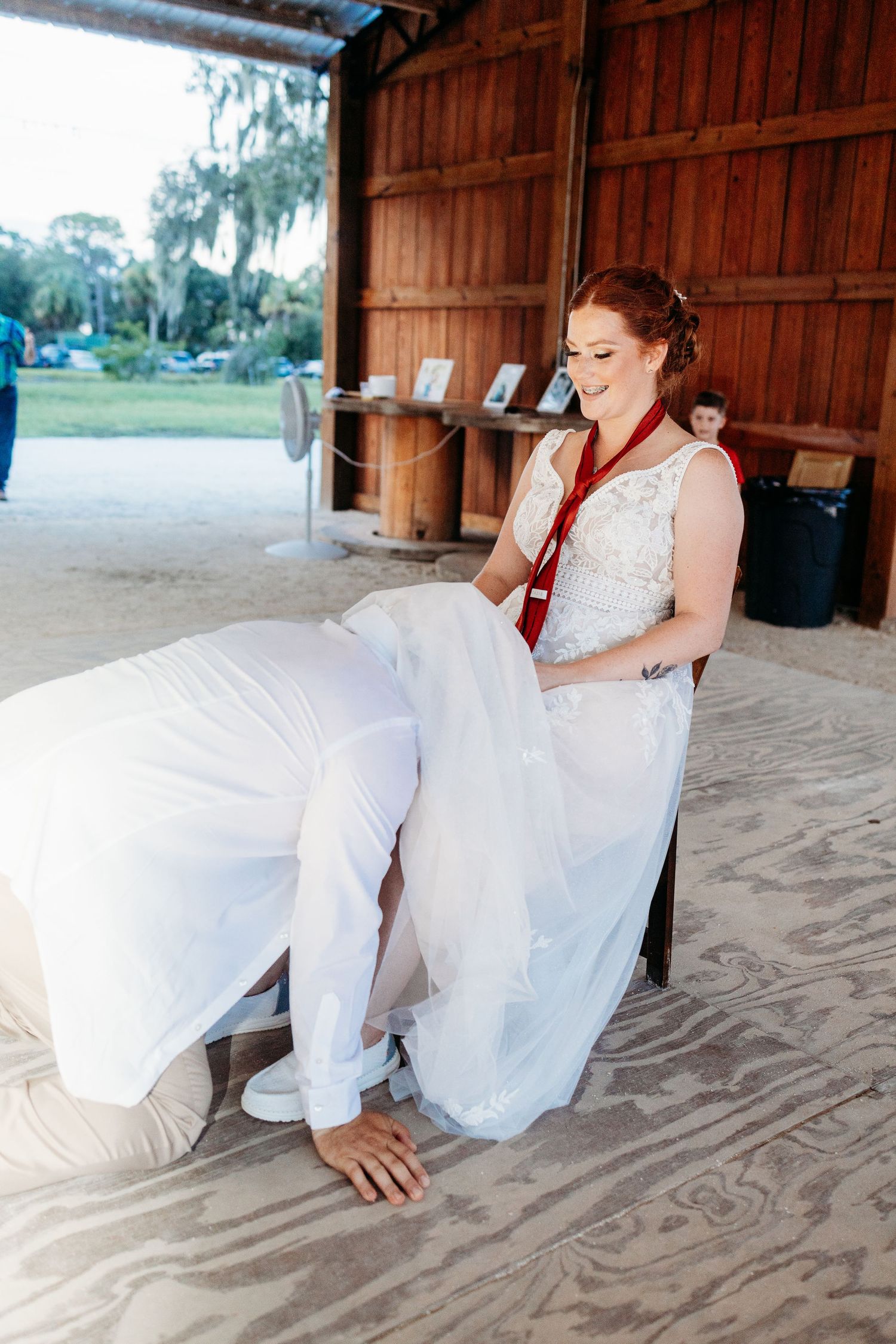 A candid moment during a wedding shows playful interaction in a rustic barn setting.