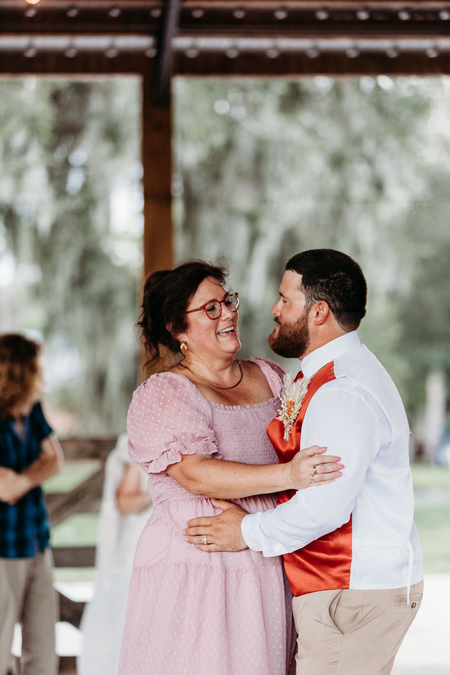 A joyful dance moment between a couple in pink and white at an outdoor reception.
