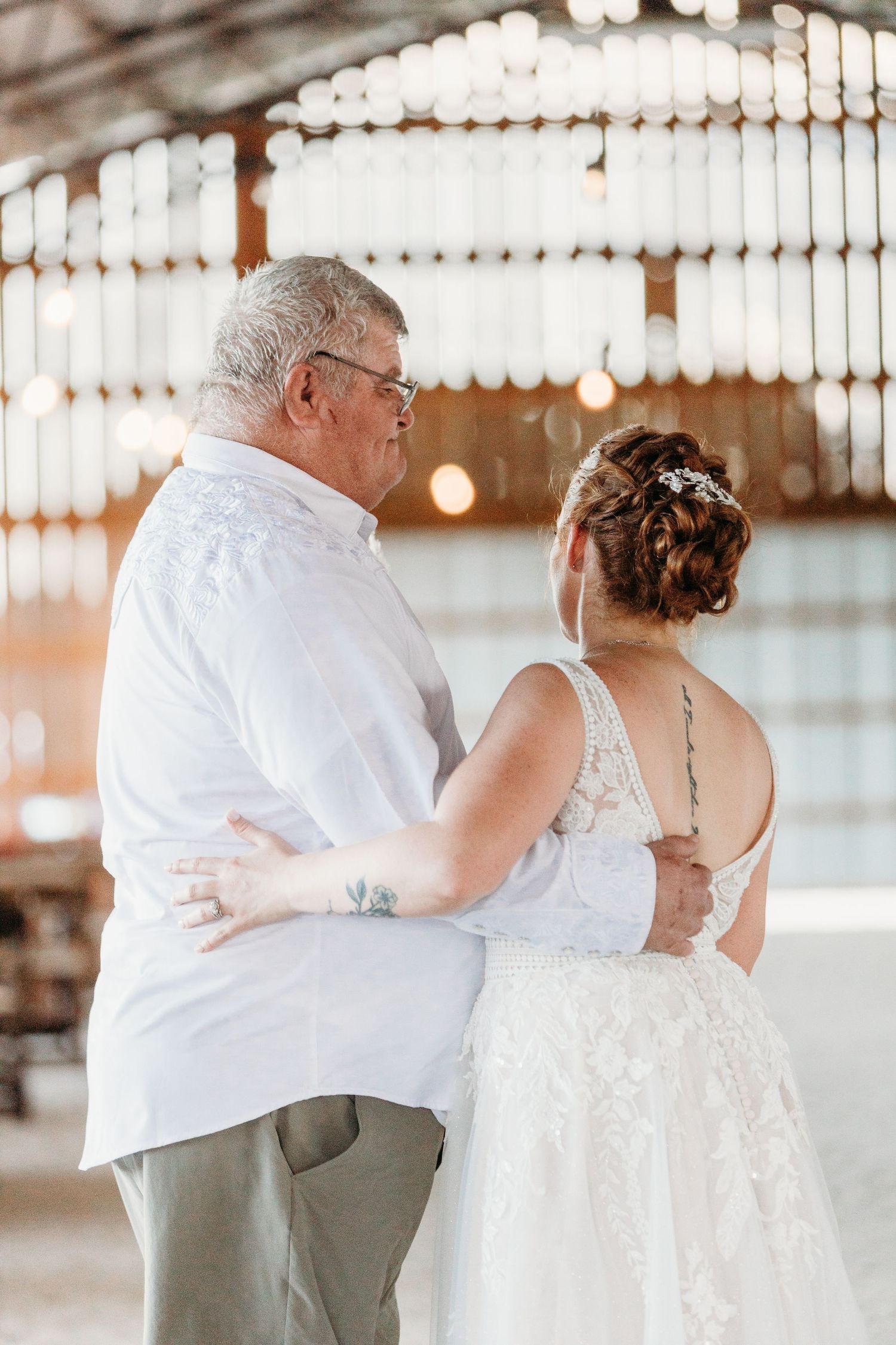 A tender moment during a wedding dance in a beautifully lit barn venue.