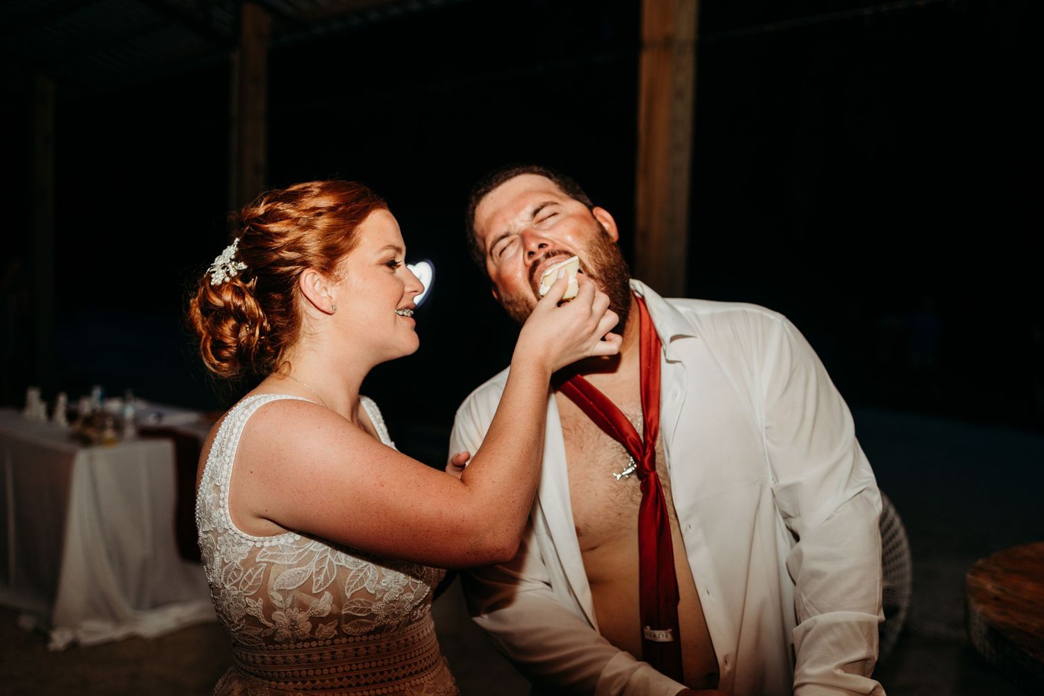 A playful cake-feeding moment between newlyweds at their reception.