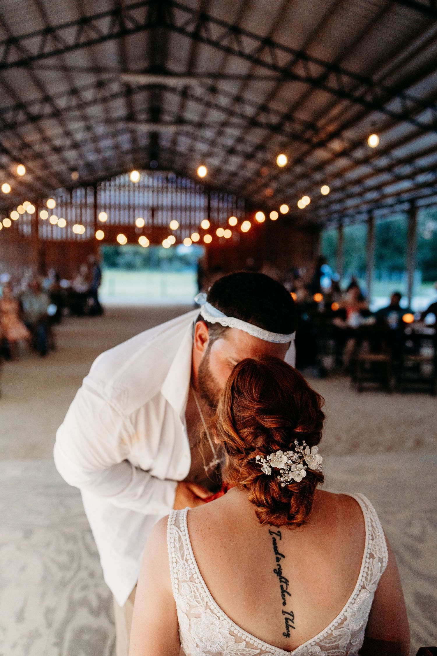 An intimate dancing moment under string lights in a rustic barn venue.