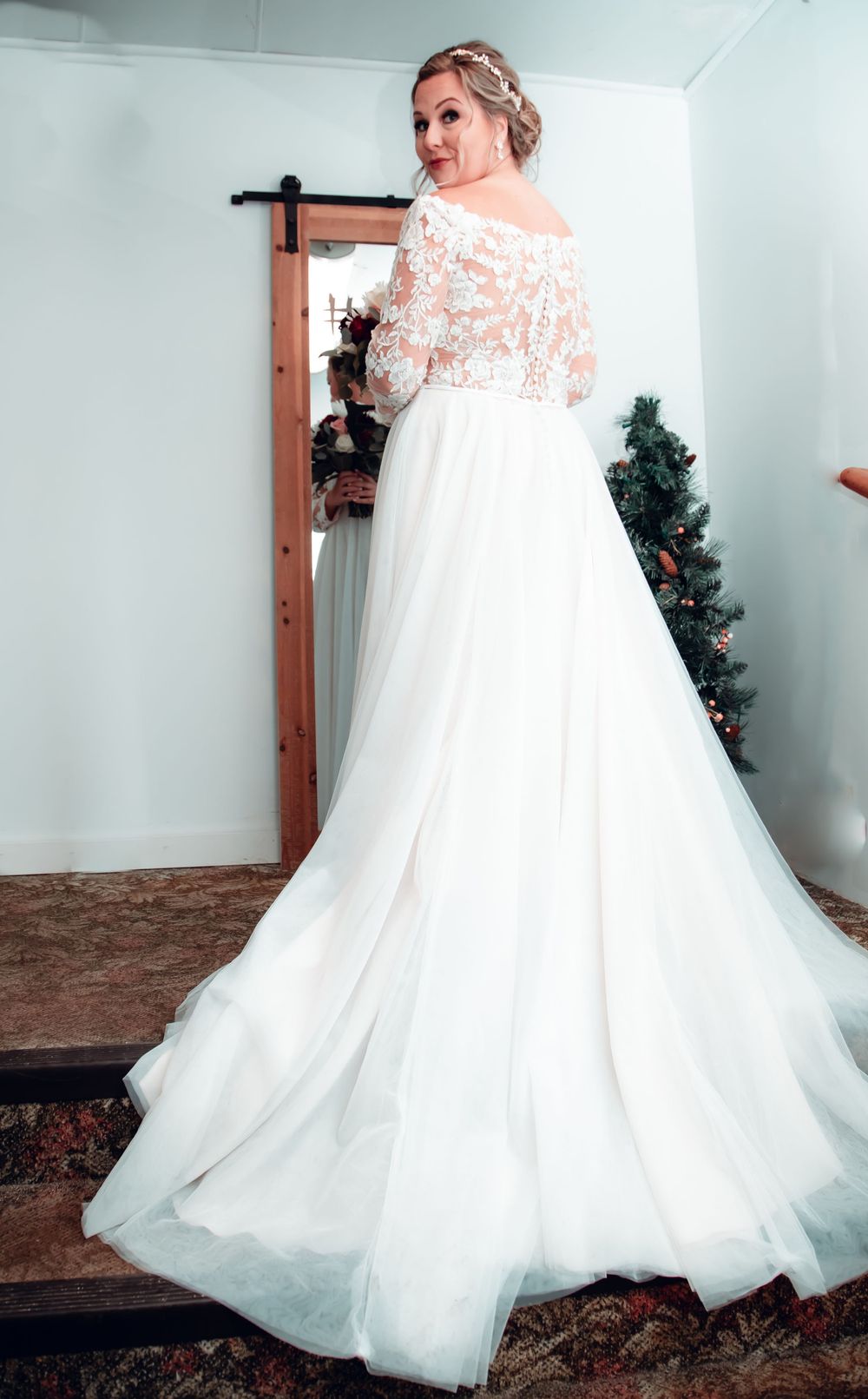 Back view of bride in off-shoulder lace wedding gown with flowing tulle skirt.