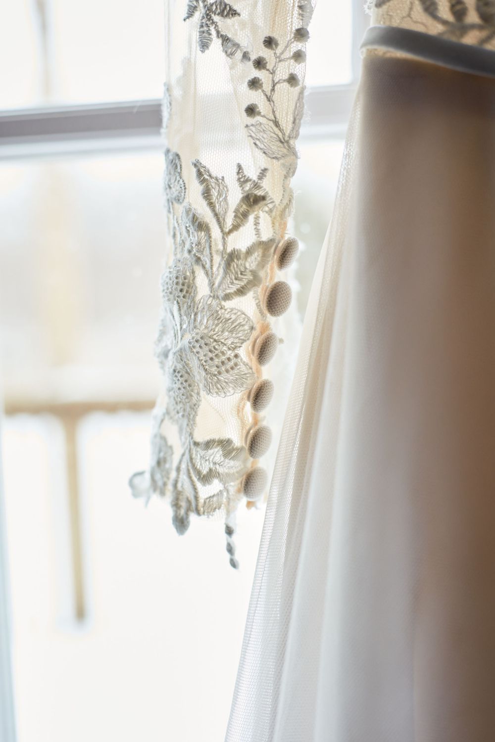 Close-up detail of delicate lace pattern on white wedding dress fabric.