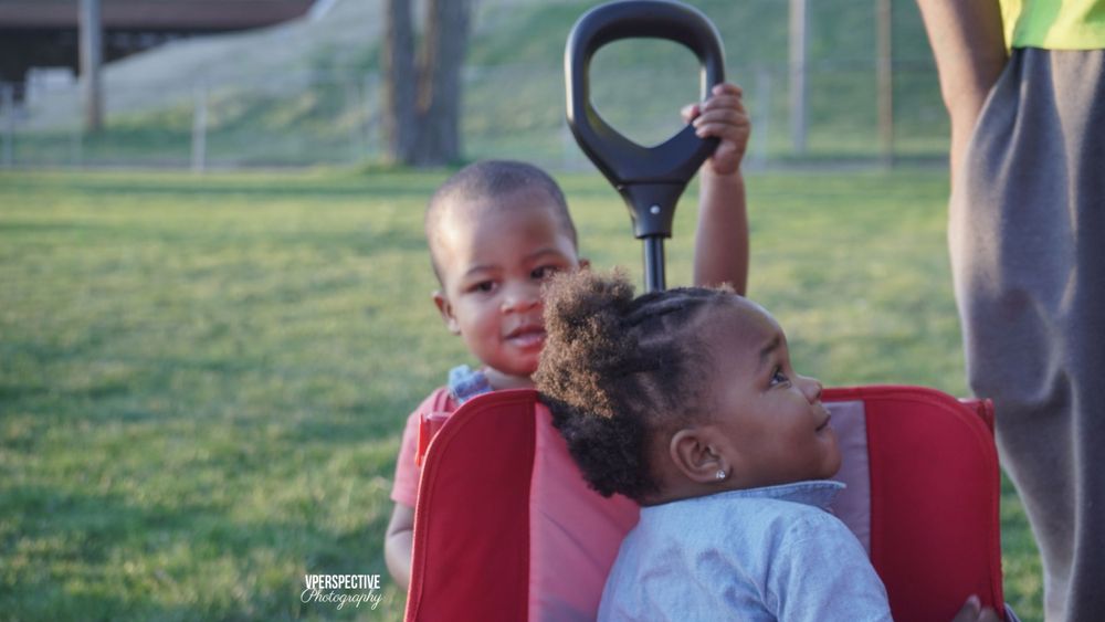 Children enjoying a ride in red wagon at park.