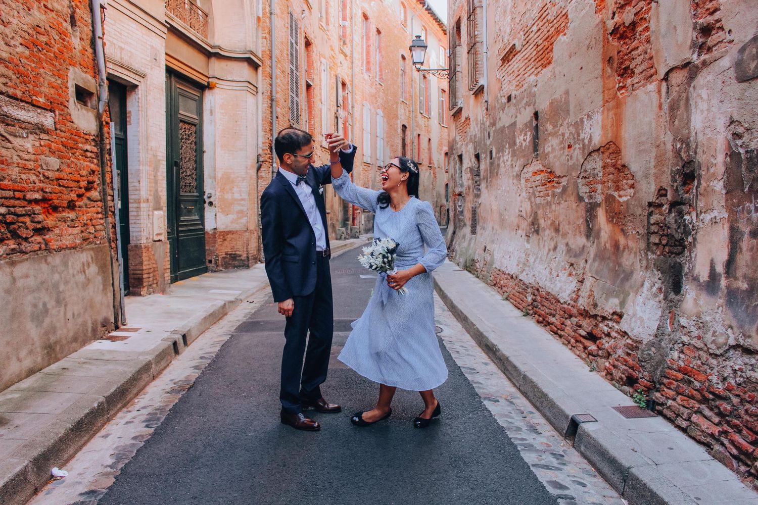 Couple sharing a romantic moment in a narrow European alleyway with rustic brick walls.