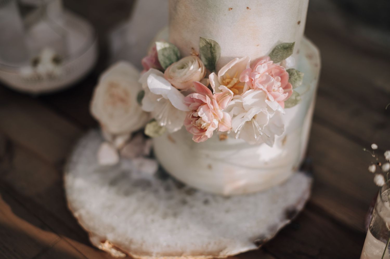 Close-up of delicate pink flowers decorating a white wedding cake tier.