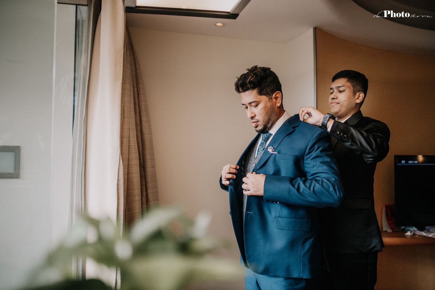 Two people in formal wear sharing a moment in a neutral-toned room setting.