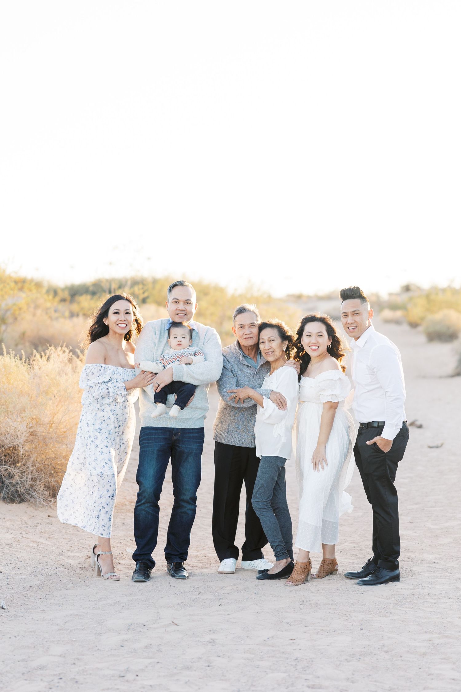 Family group photo session on sandy terrain at sunset.