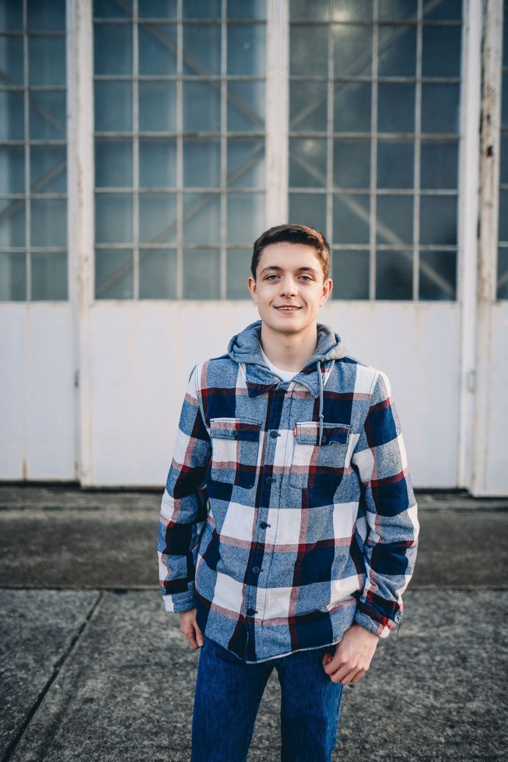 Person wearing plaid flannel shirt and jeans in an industrial space.