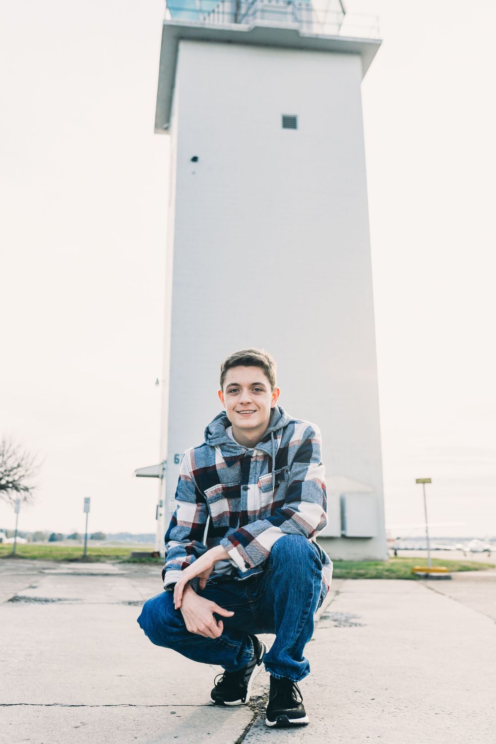 Person posing near a white lighthouse structure on an overcast day.