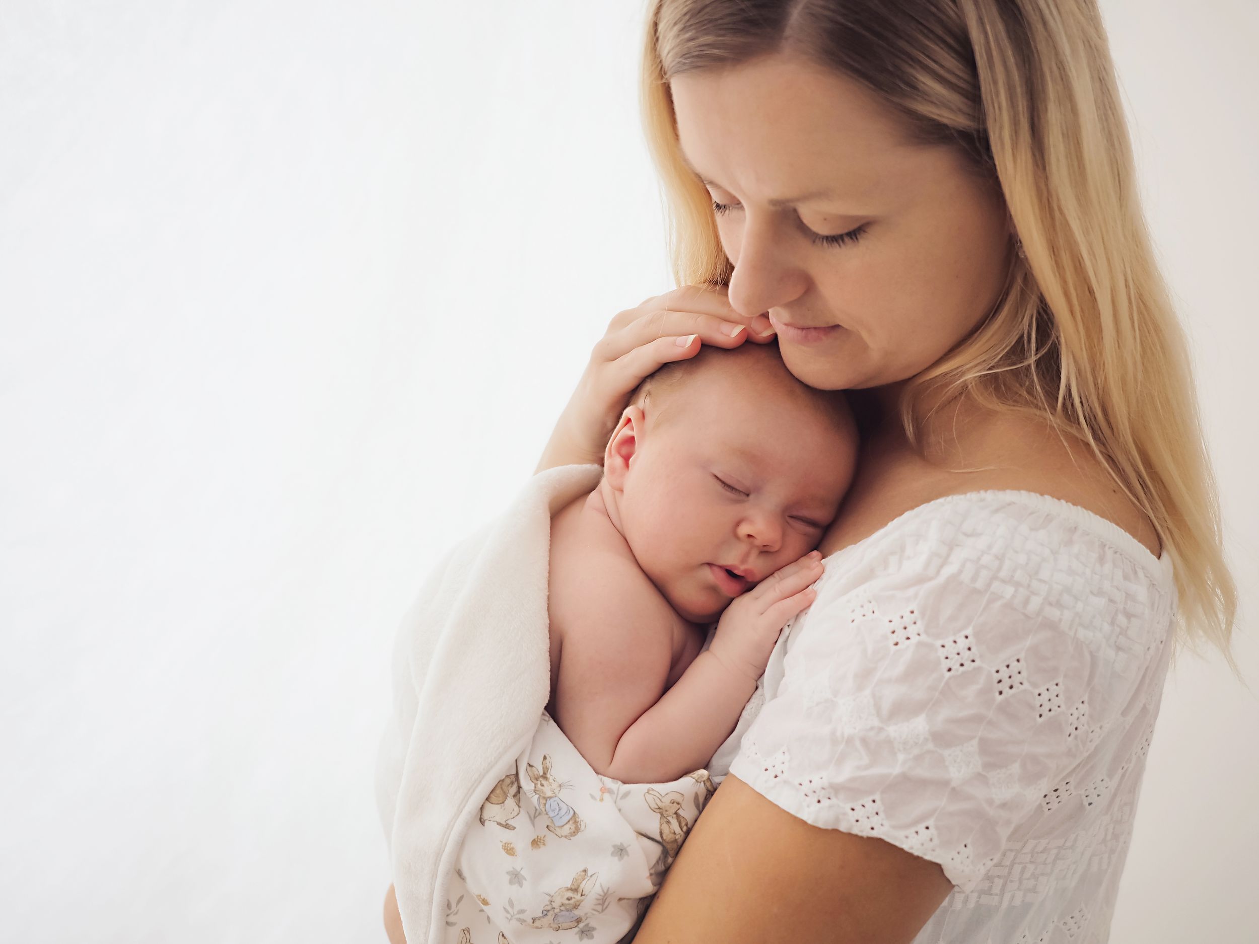 Portrait of a mother holding newborn baby wrapped in white blanket by Didcot studio Verity Photography