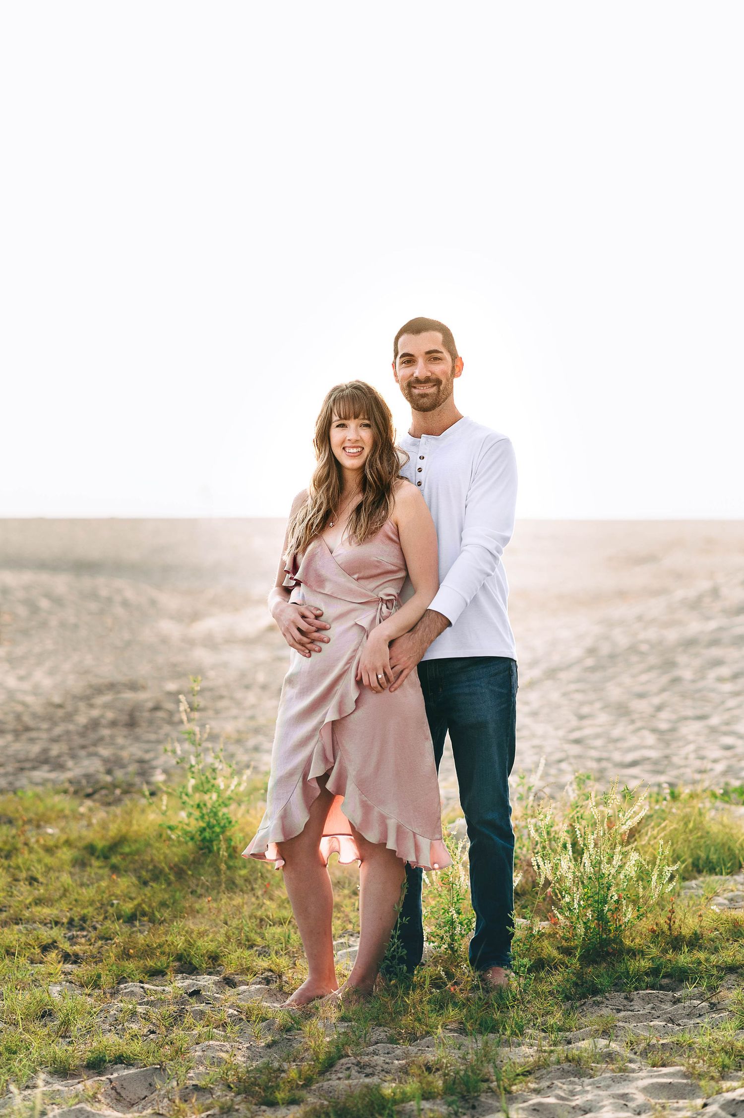 Happy couple embraces outdoors in a desert setting during golden hour.