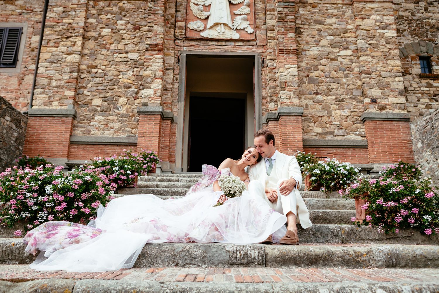 bride and groom sitting on steps outside the church in Panzano Tuscany Italy