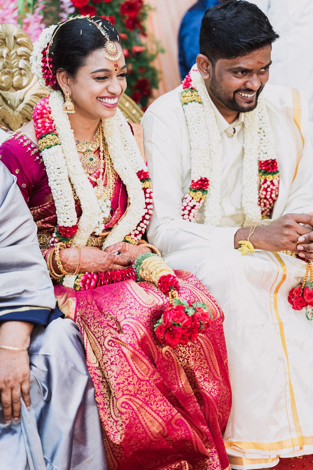 Wedding couple in traditional South Indian attire sharing a joyful moment during ceremony.