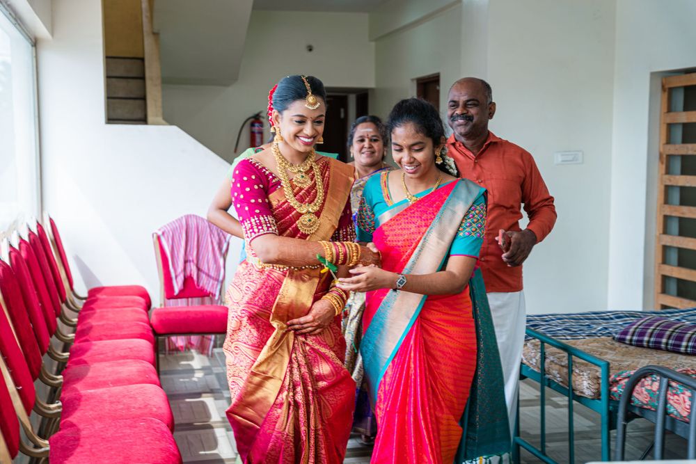 Joyful celebration with participants wearing vibrant traditional Indian sarees in red and pink.