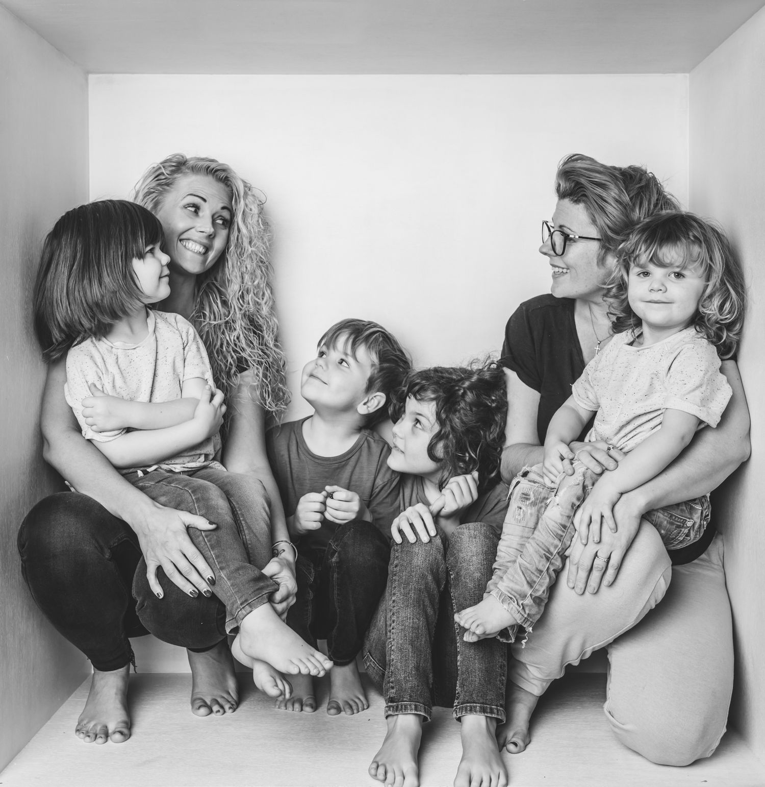 black & white image of 4 little boys and 2 women huddled together all smiling