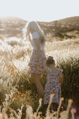 Sun-lit scene of matching floral dresses in a golden meadow at sunset.