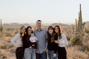 A family photo taken in the Arizona desert with tall saguaros in the background.
