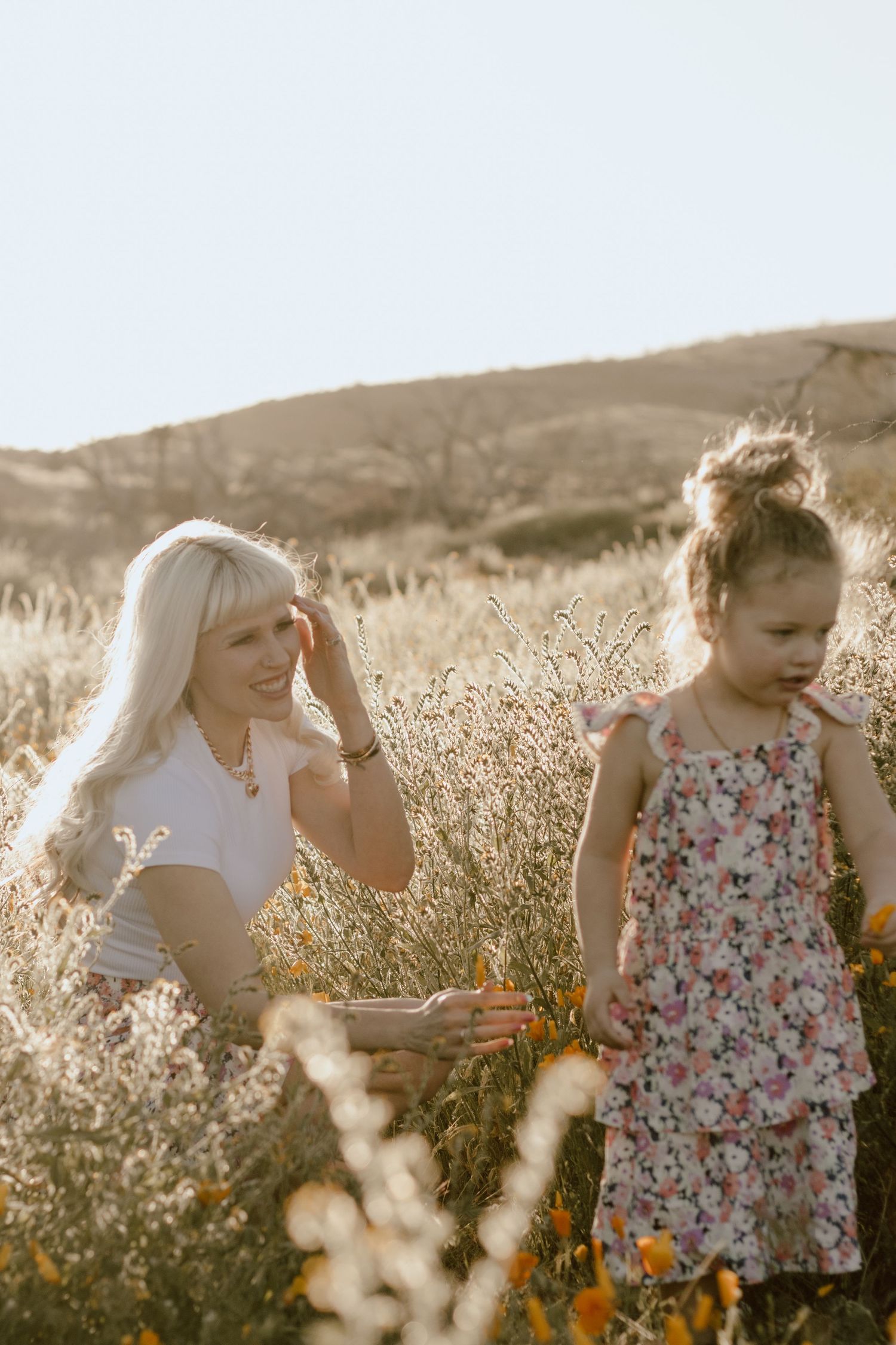 A sunlit meadow scene with matching floral dresses among wildflowers.