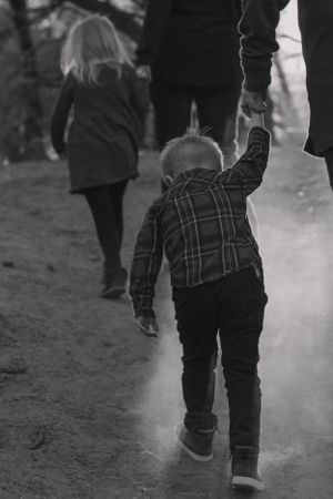 A black and white image of figures walking along a dusty path together.